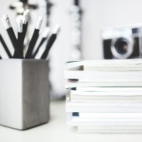 审校人员在明亮办公桌前逐条核对文稿中的数字与口径，手边放着标注笔与打印稿